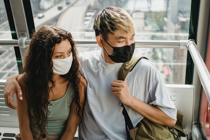 Jovem casal com máscaras de pano em transporte público