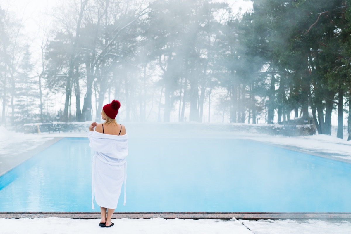 mulher com manto entrando na piscina em um dia frio de inverno