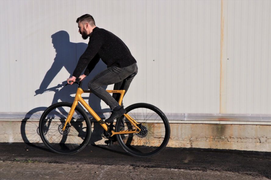 Uma pessoa andando de bicicleta amarela, indo para a esquerda.