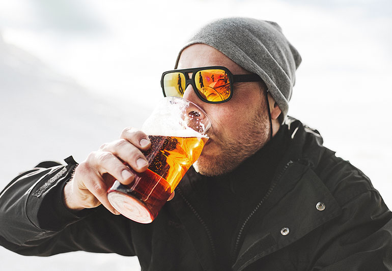 Homem tomando uma cerveja lá fora durante o inverno