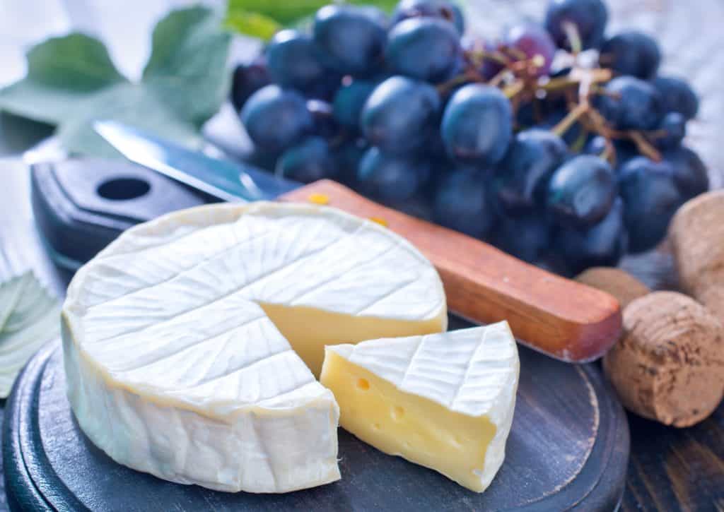 queijo camembert e uvas em uma tábua