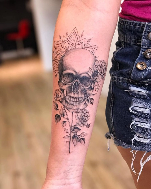 tatuagem de caveira no antebraço com flores