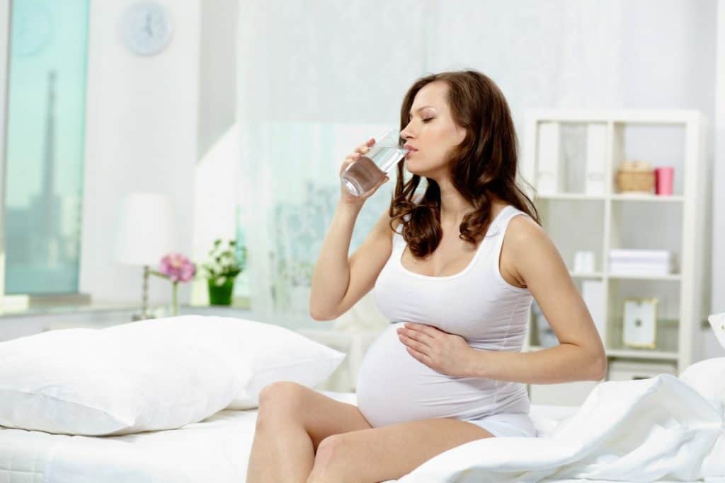 mulher grávida no terceiro trimestre bebendo água