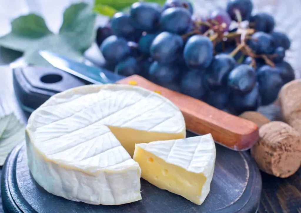 camembert cheese and grapes on a cutting board