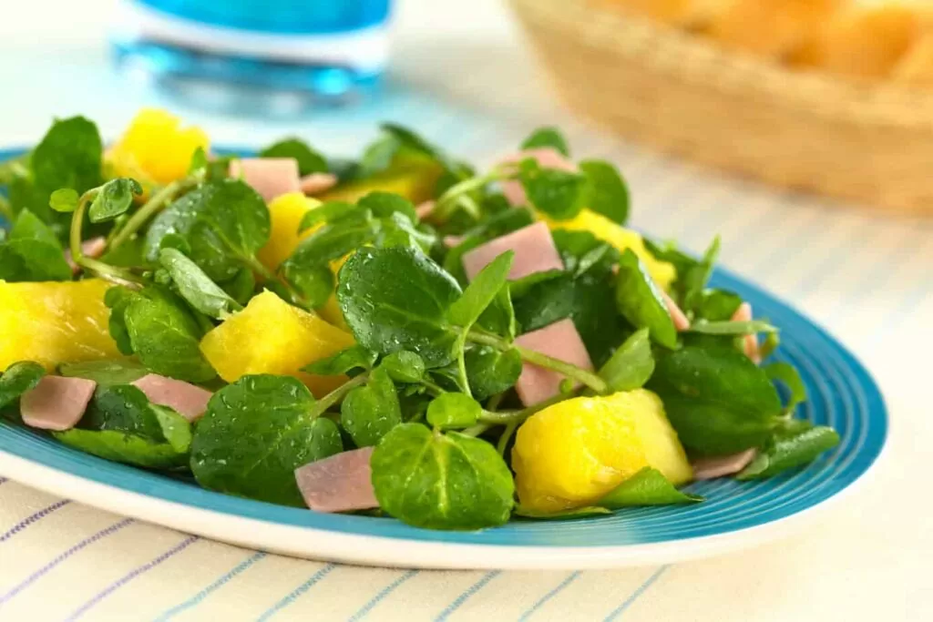 watercress salad with pineapple and ham on a plate